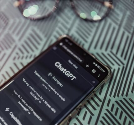 Smartphone with ChatGPT app interface next to eyeglasses on patterned surface.