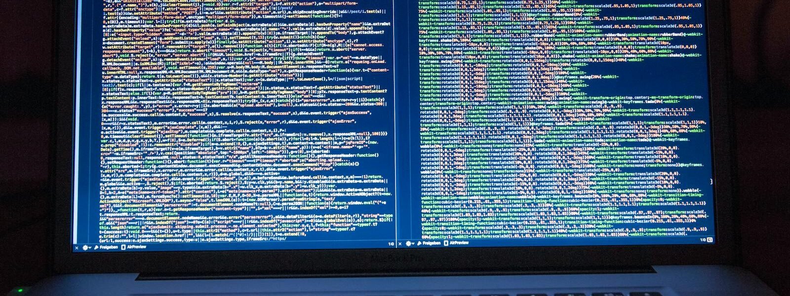 Laptop displaying source code with dual screens for software development.