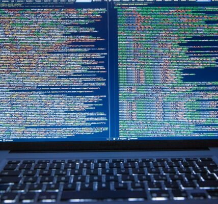 Laptop displaying source code with dual screens for software development.