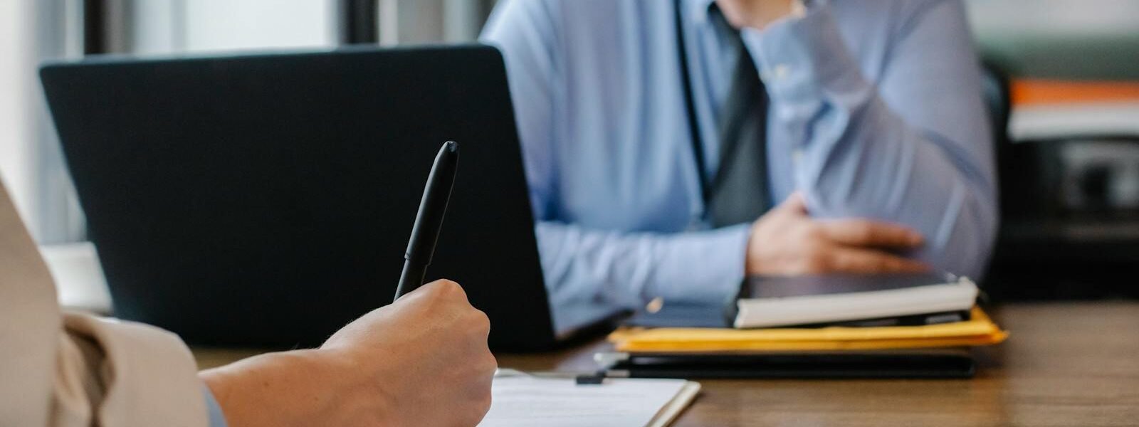 Crop anonymous female filling questionnaire when applying for job sitting in employer office