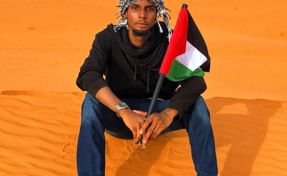 man in diffa desert holding palestinian flag
