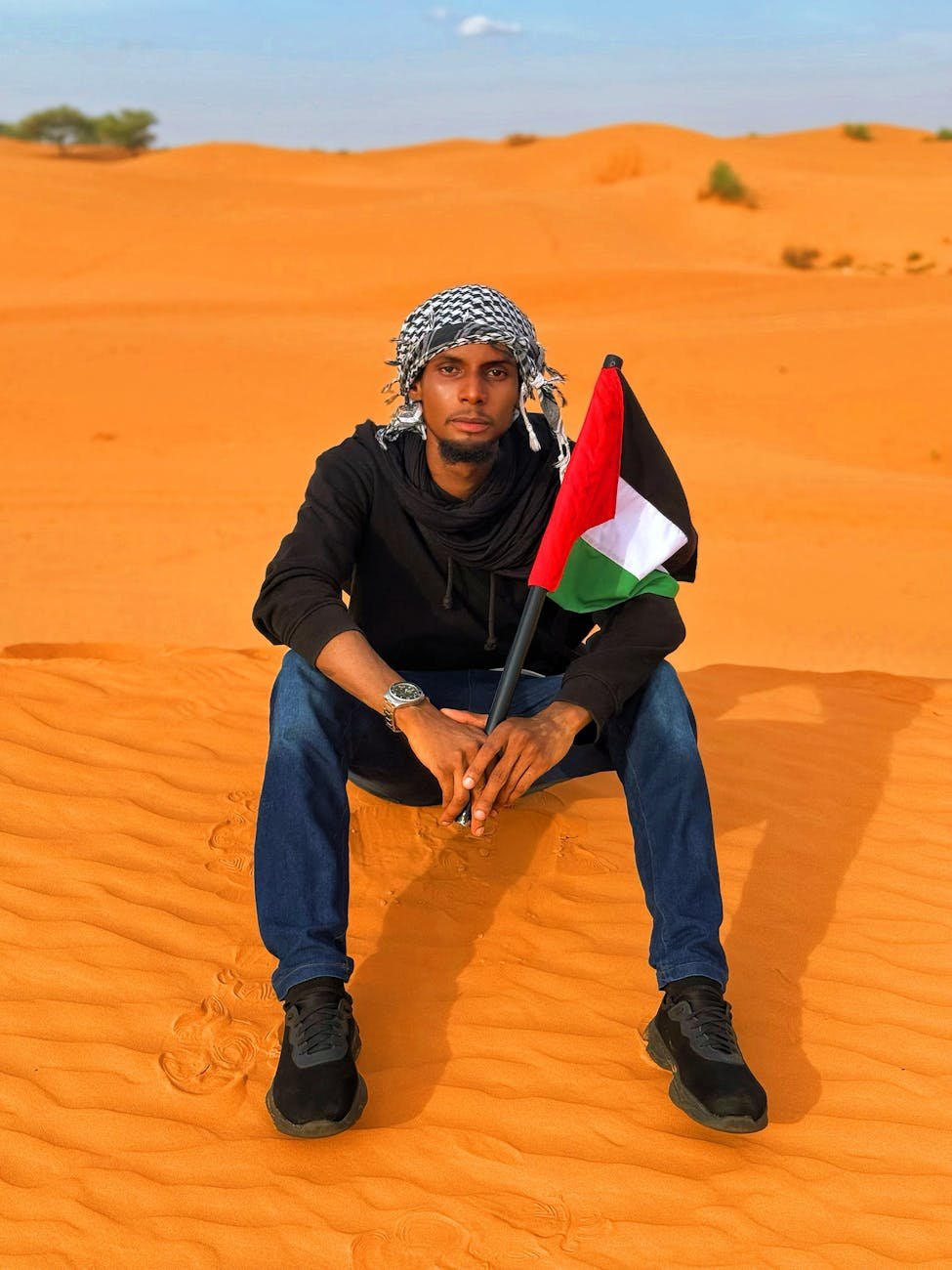 man in diffa desert holding palestinian flag