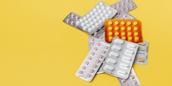 heap of various pills in blisters on yellow background