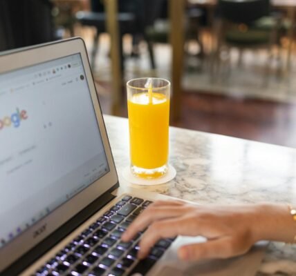 woman using a computer laptop near a glass of juice