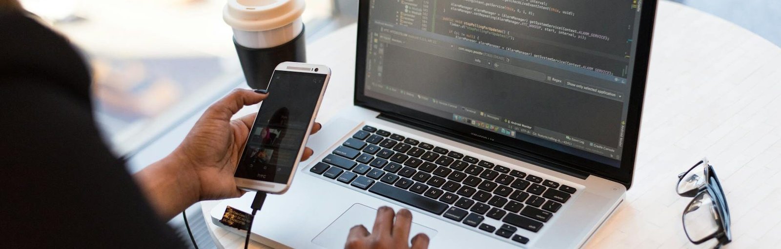 person holding smartphone while using laptop