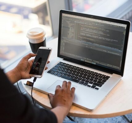 person holding smartphone while using laptop