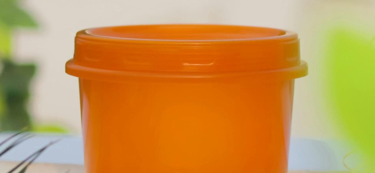 an orange plastic container on a wooden board